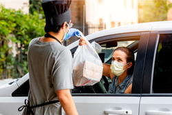 Worker Wearing PPE Delivering Food Safely to Masked Women